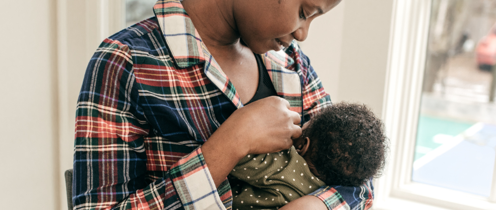 Woman in plaid shirt breastfeeding a baby