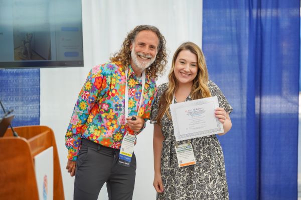 Courtney Fleming posing with the award and another person, both smiling broadly.