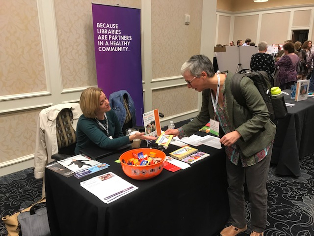 Two women talking at the LHI booth at a community event