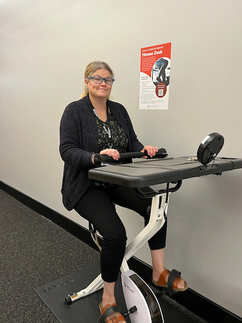 Kerry Dhakal, Health Sciences Library research and education librarian, tries out a FitDesk on the library's first floor.