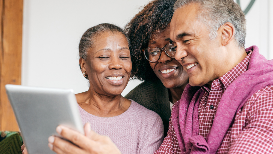 Three individuals look at a tablet device.