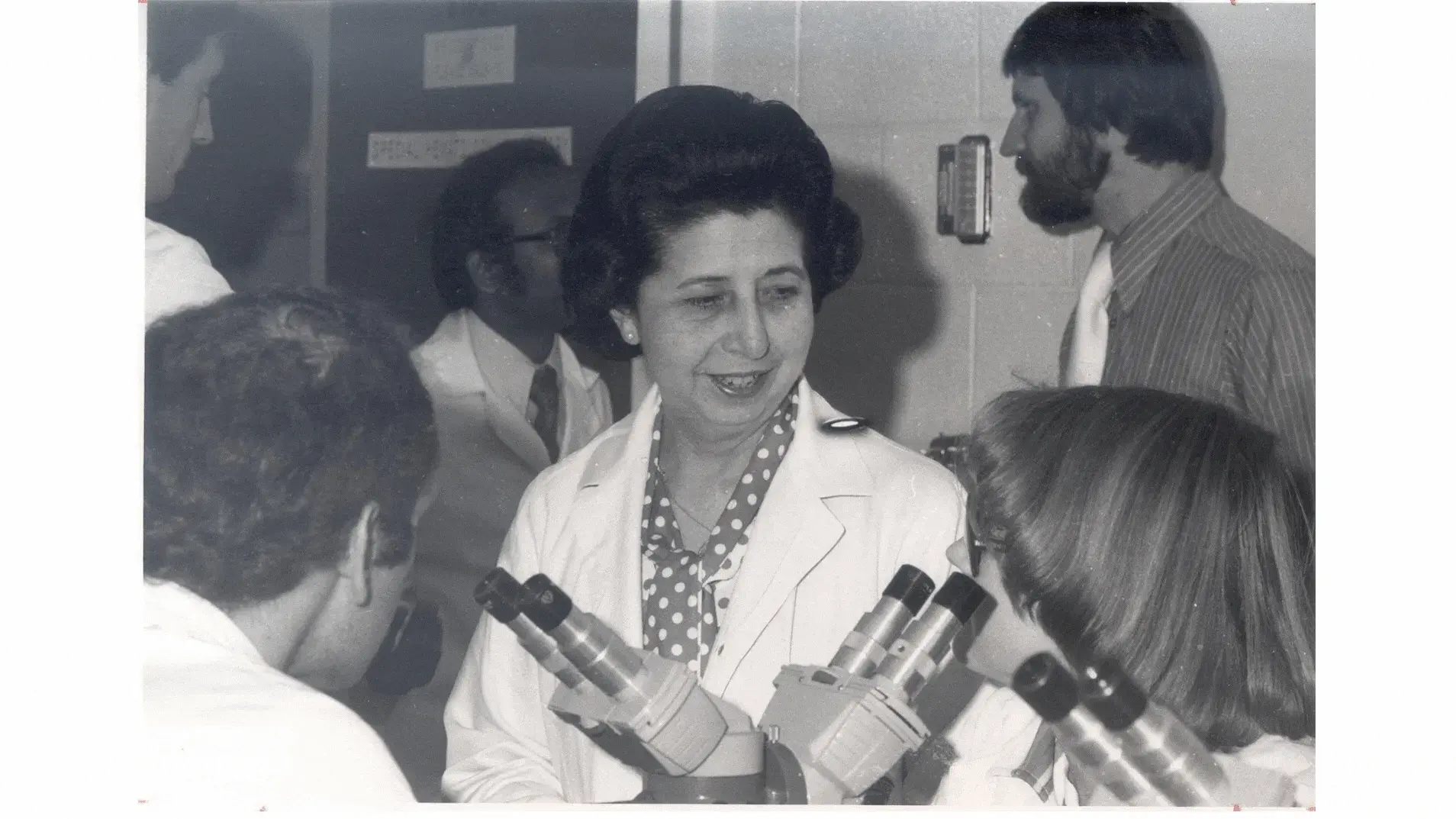 Bertha Bouroncle with a group of students looking through microscopes
