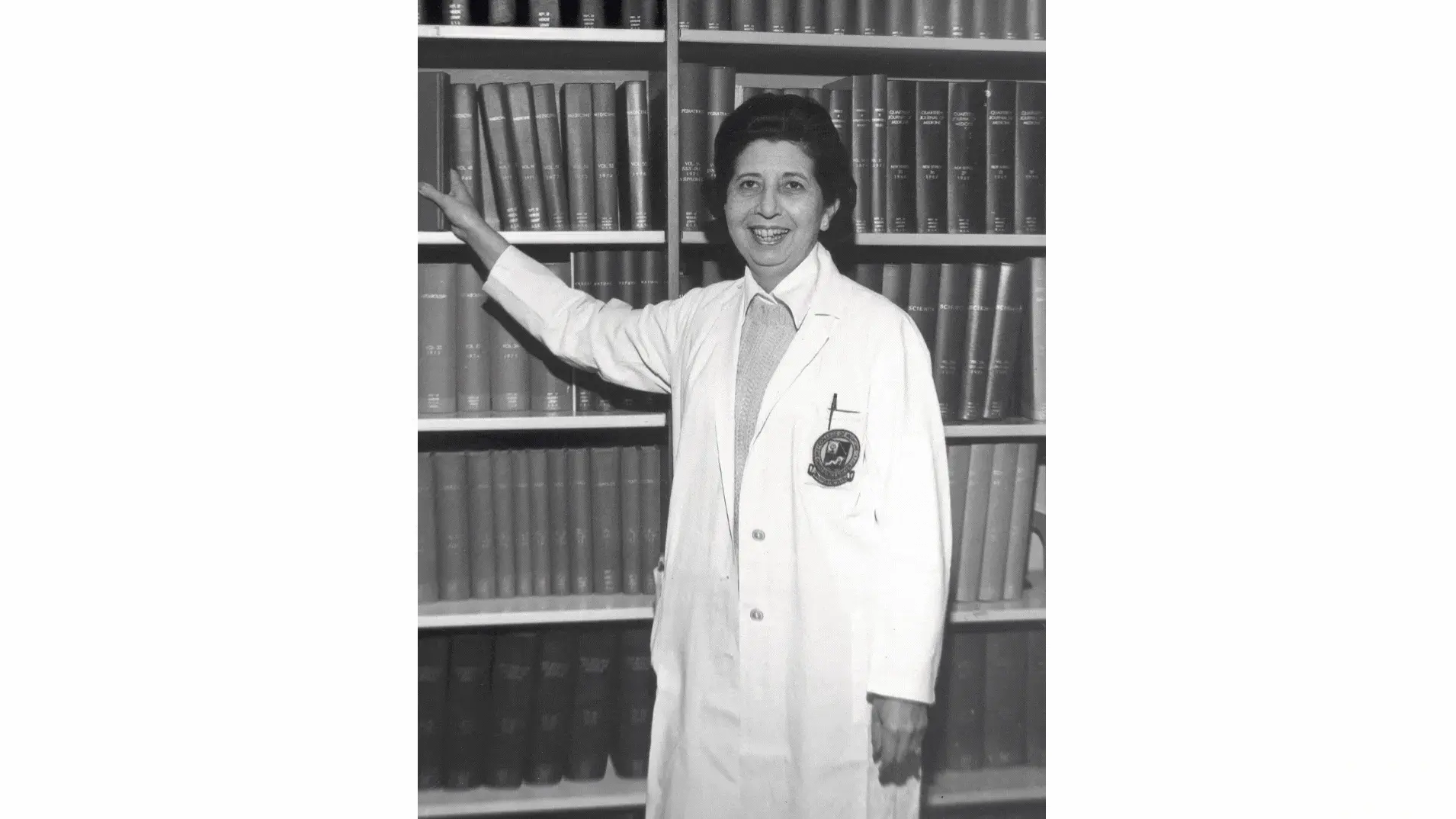 Bertha Bouroncle poses for a portrait in front of a medical library of books on shelves