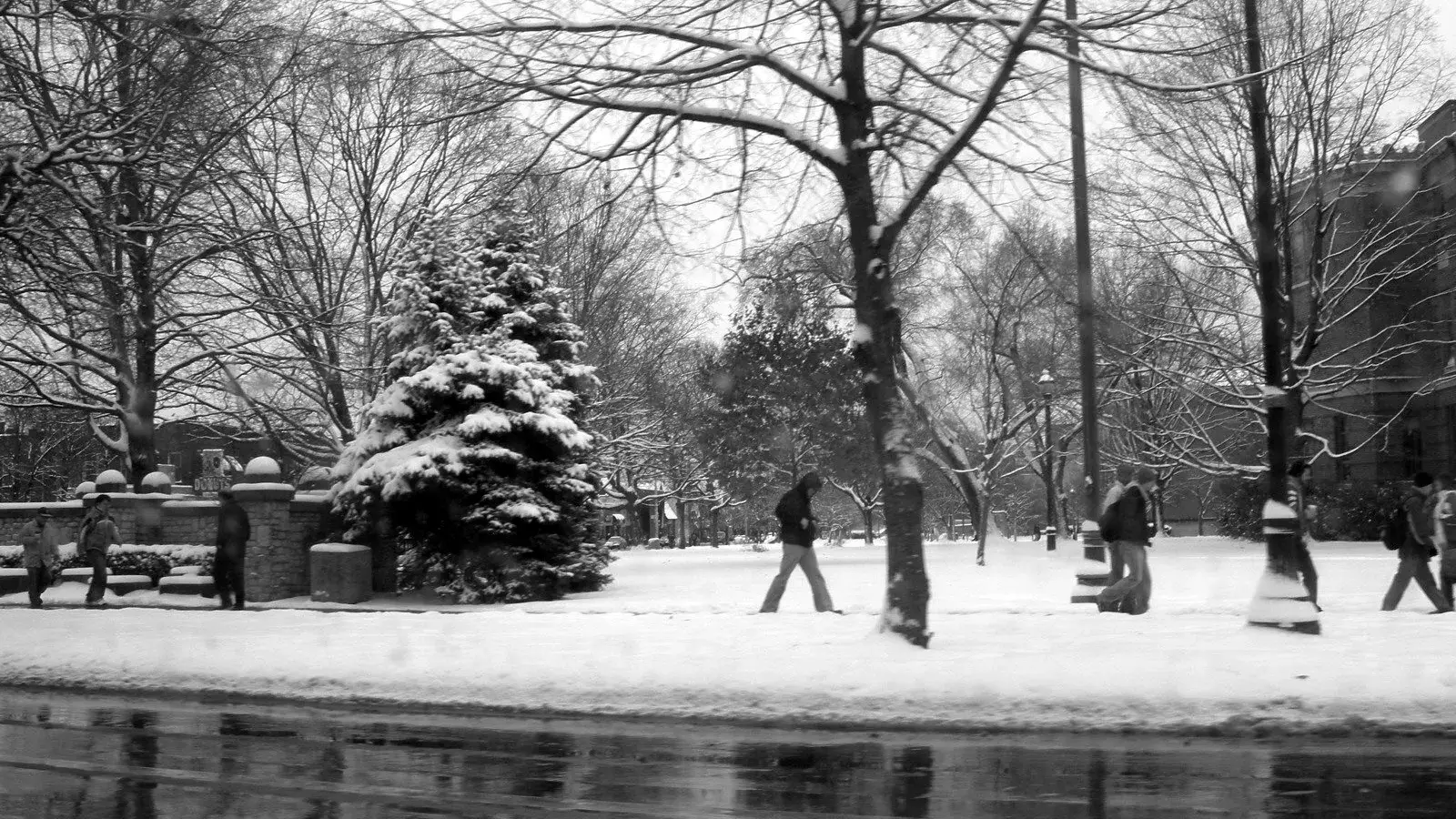 black and white view of students walking through campus on a snowy winter morning
