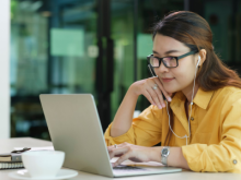 Woman with headphones in looking at her laptop