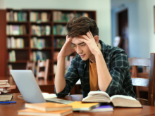 student sitting at computer with books on the table