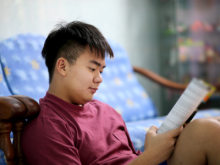 student sitting next to a couch reading a magazine