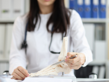 woman using pen to point to bone model of a foot and ankle