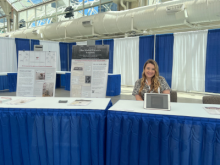 Courtney Chenock smiling at a conference with Medical Visuals' coloring book.
