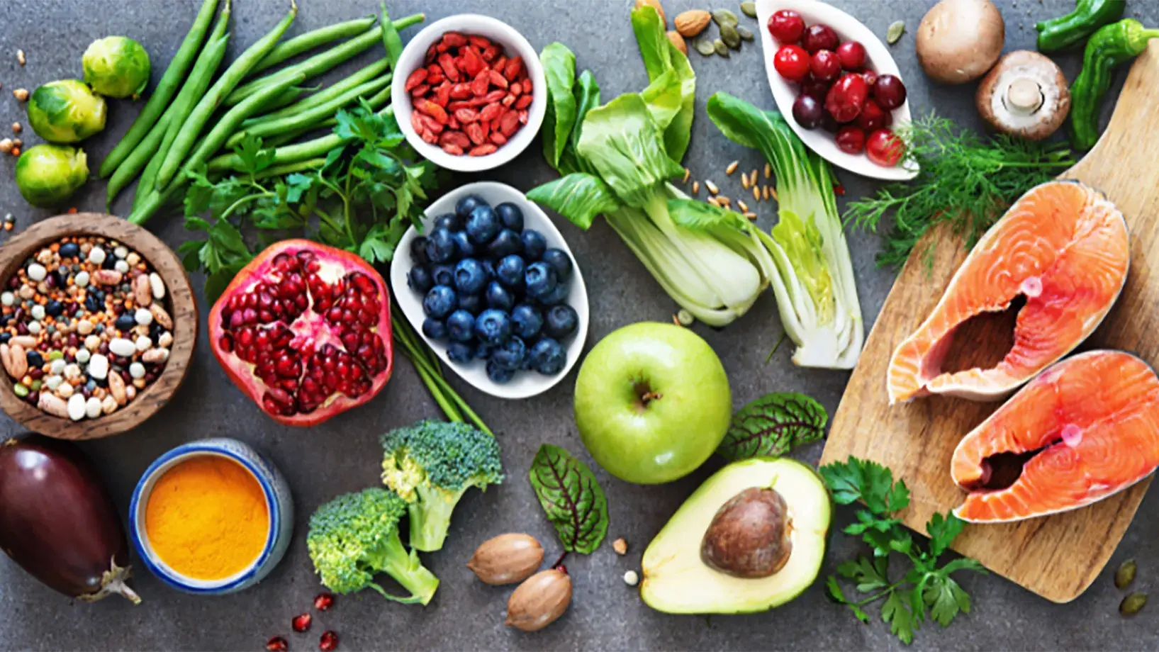 colorful array of good health foods like leafy greens, salmon, beans and eggplant