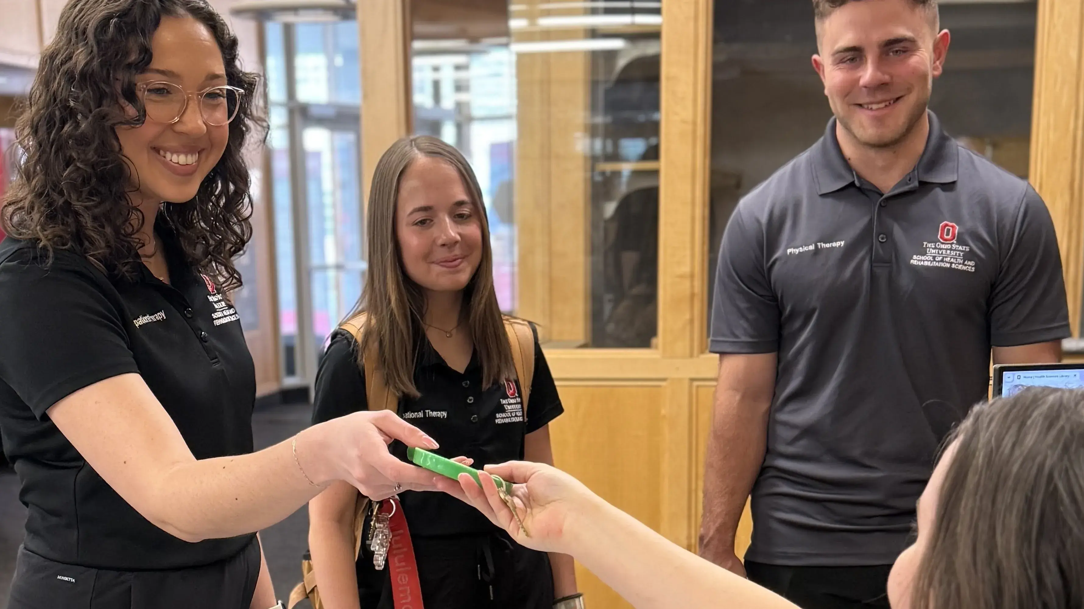 Students borrow an item from a library desk staff member
