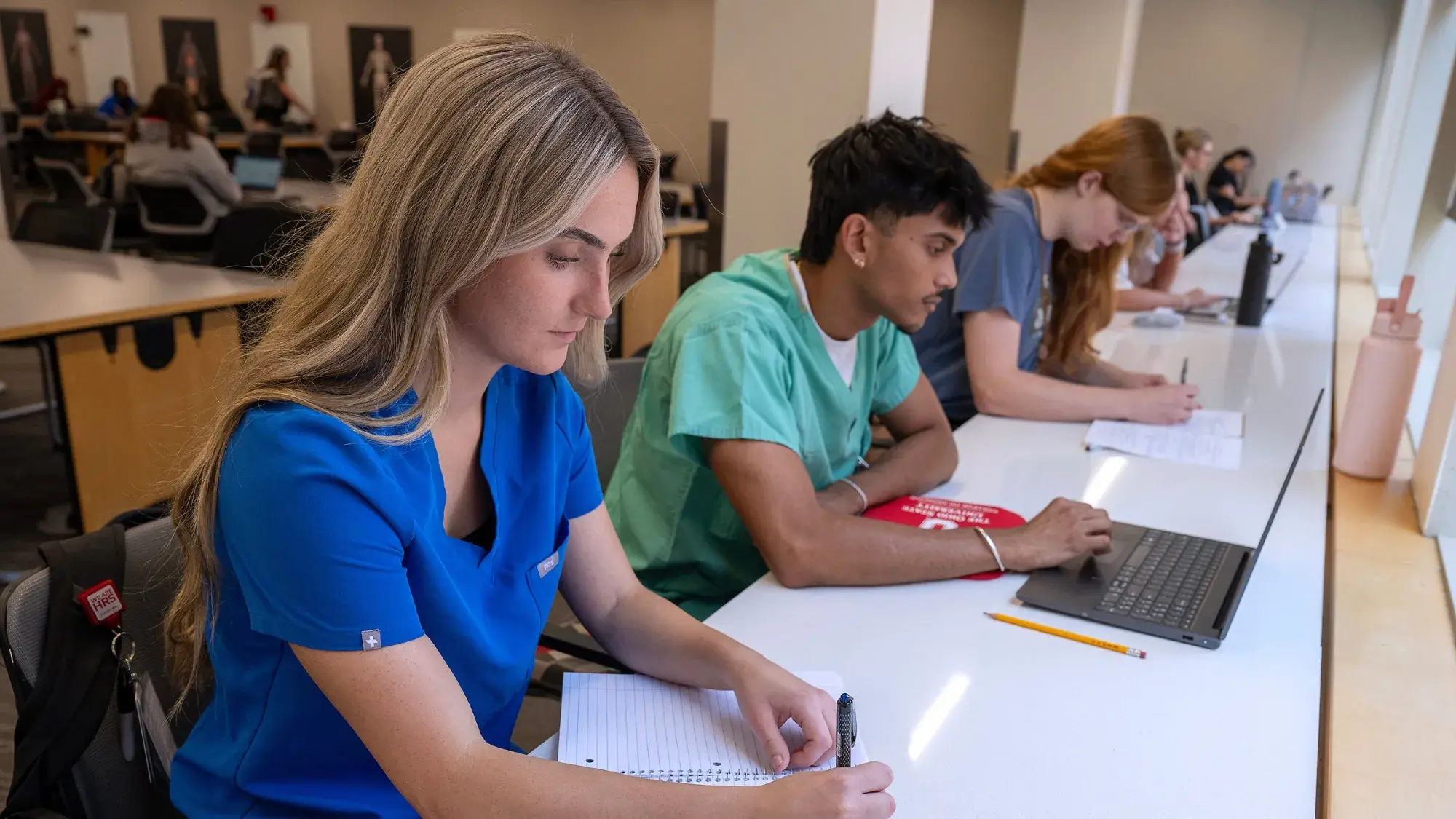 Three students writing in the library.
